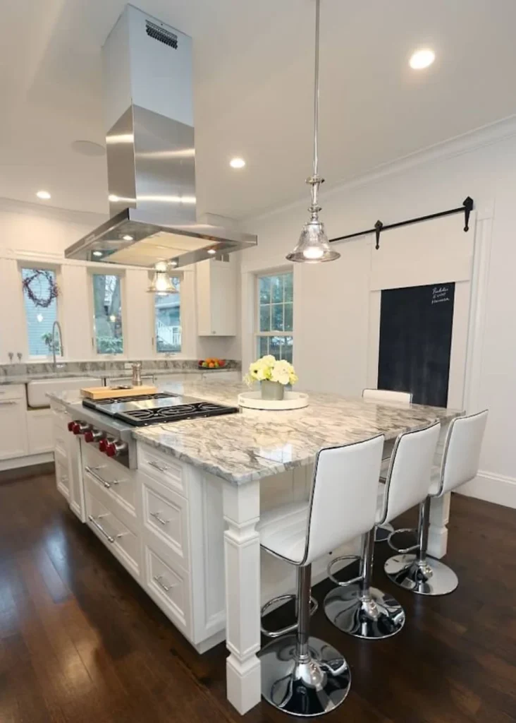 Elegant white kitchen with large center island, stainless steel range hood, and high-end finishes